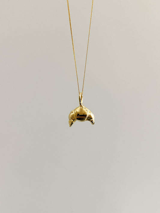 Gold croissant necklace on grey background