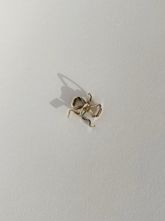Gold bow charm on white background