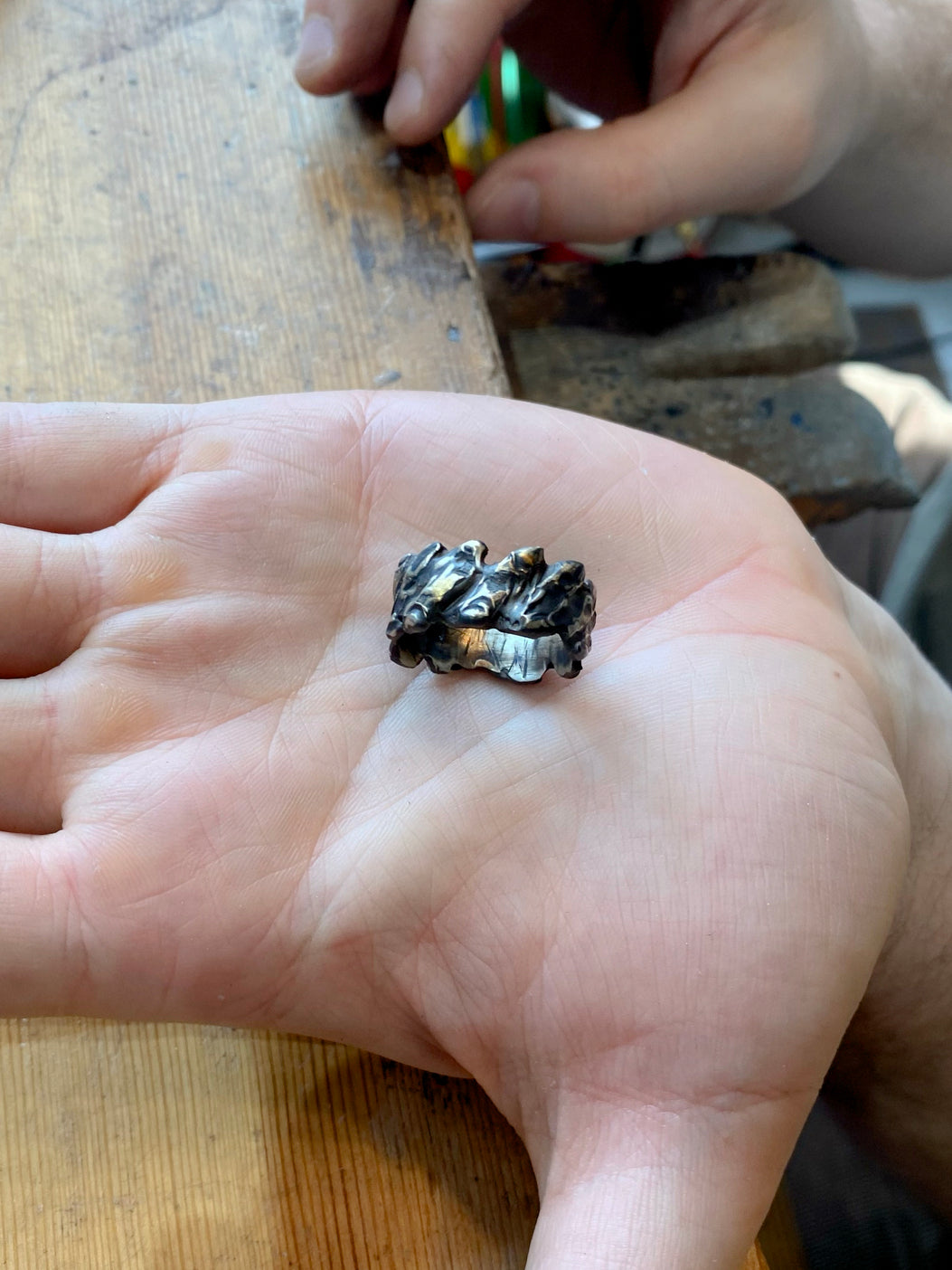 Oxidized textured silver ring in palm on wooden table