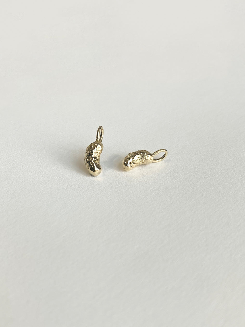 Gold pickle charms on white background