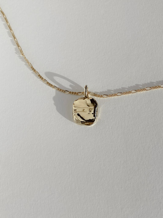 Textured gold molten pendant necklace on white background