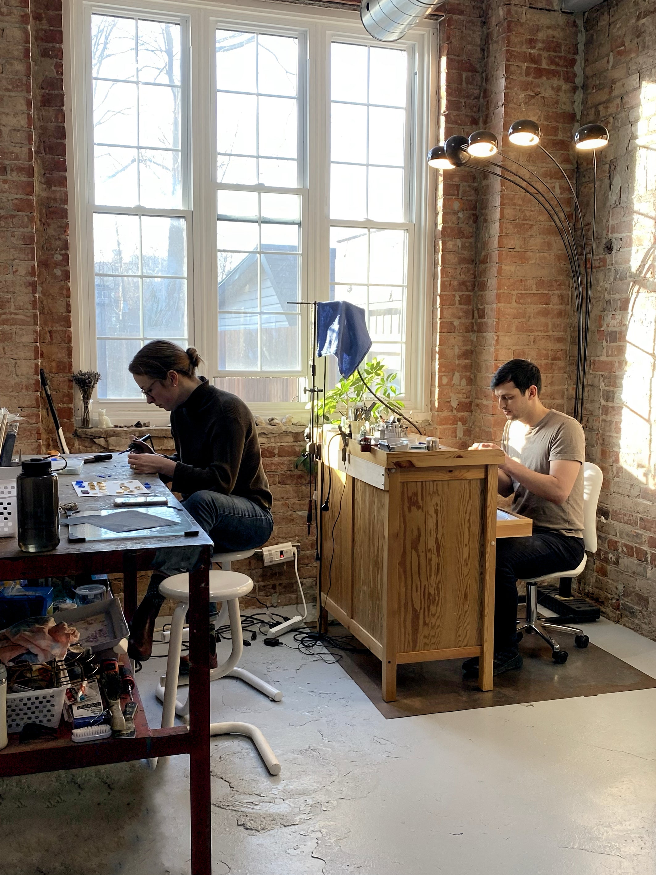 Couple working in jewellery studio making rings