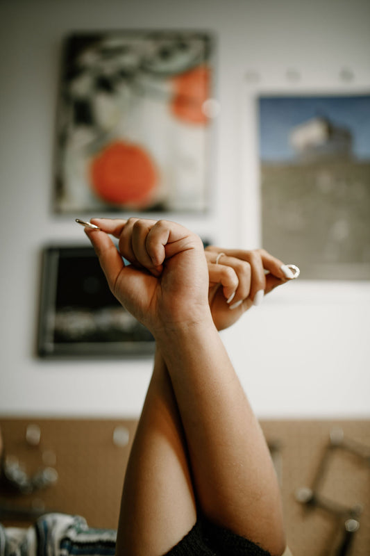 Two hands in the air holding a ring each in front of a wall of art