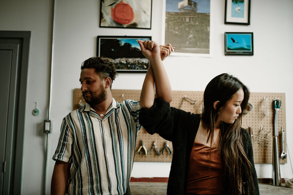 Couple with interlaced arms holding up their wedding rings