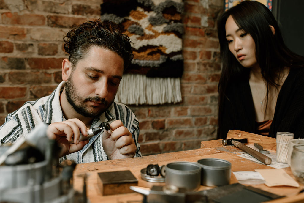 Couple working at jewellery bench polishing gold ring