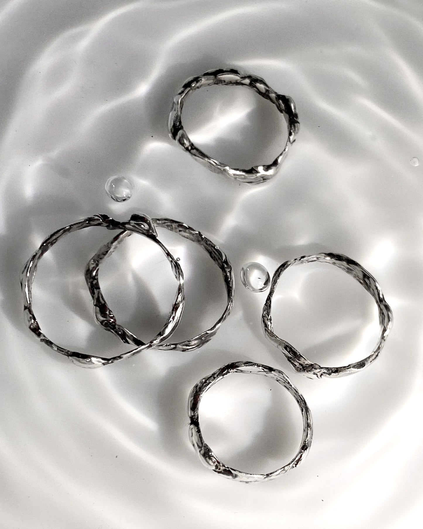 5 silver molten rings dropped in water