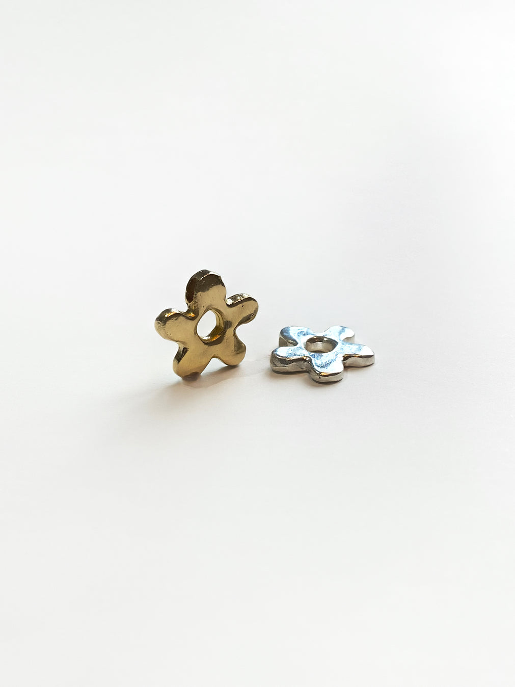 Gold and silver daisy pendants on white background