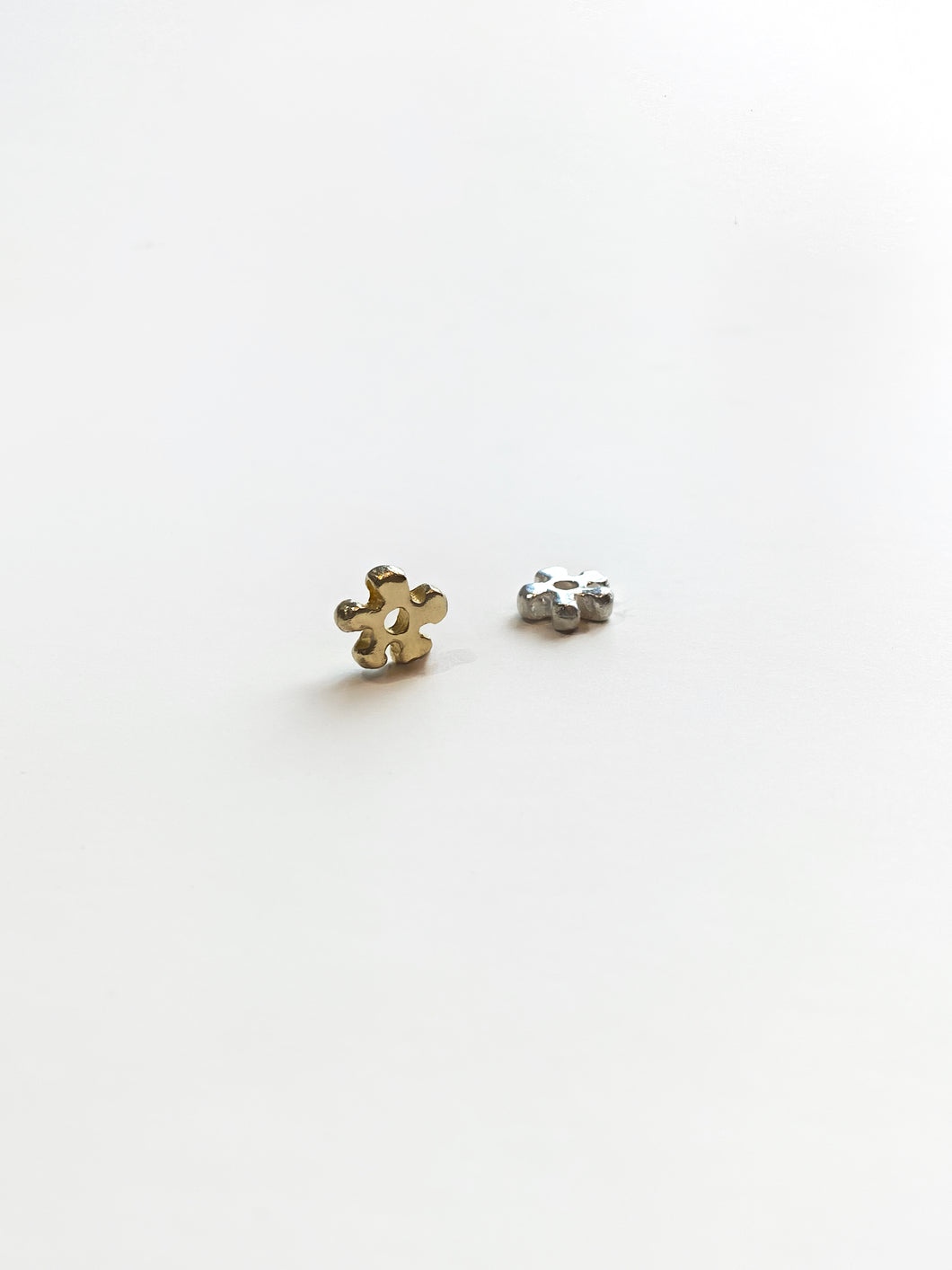 Gold and silver daisy charms on white background