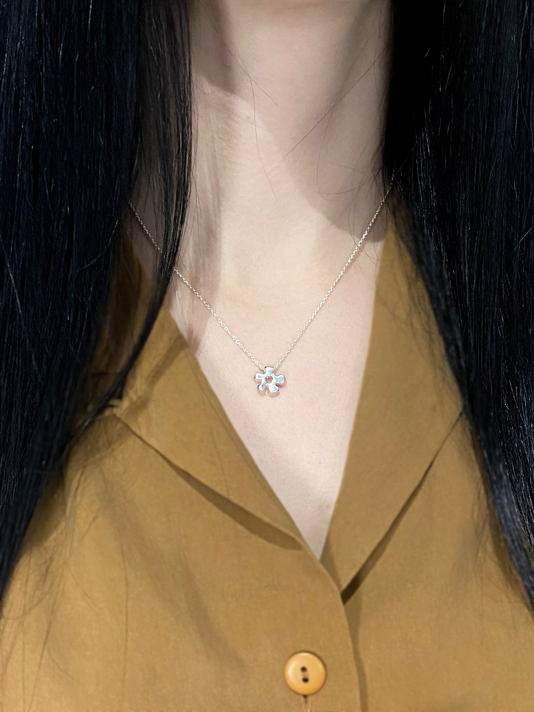 Silver daisy pendant necklace on model with brown shirt