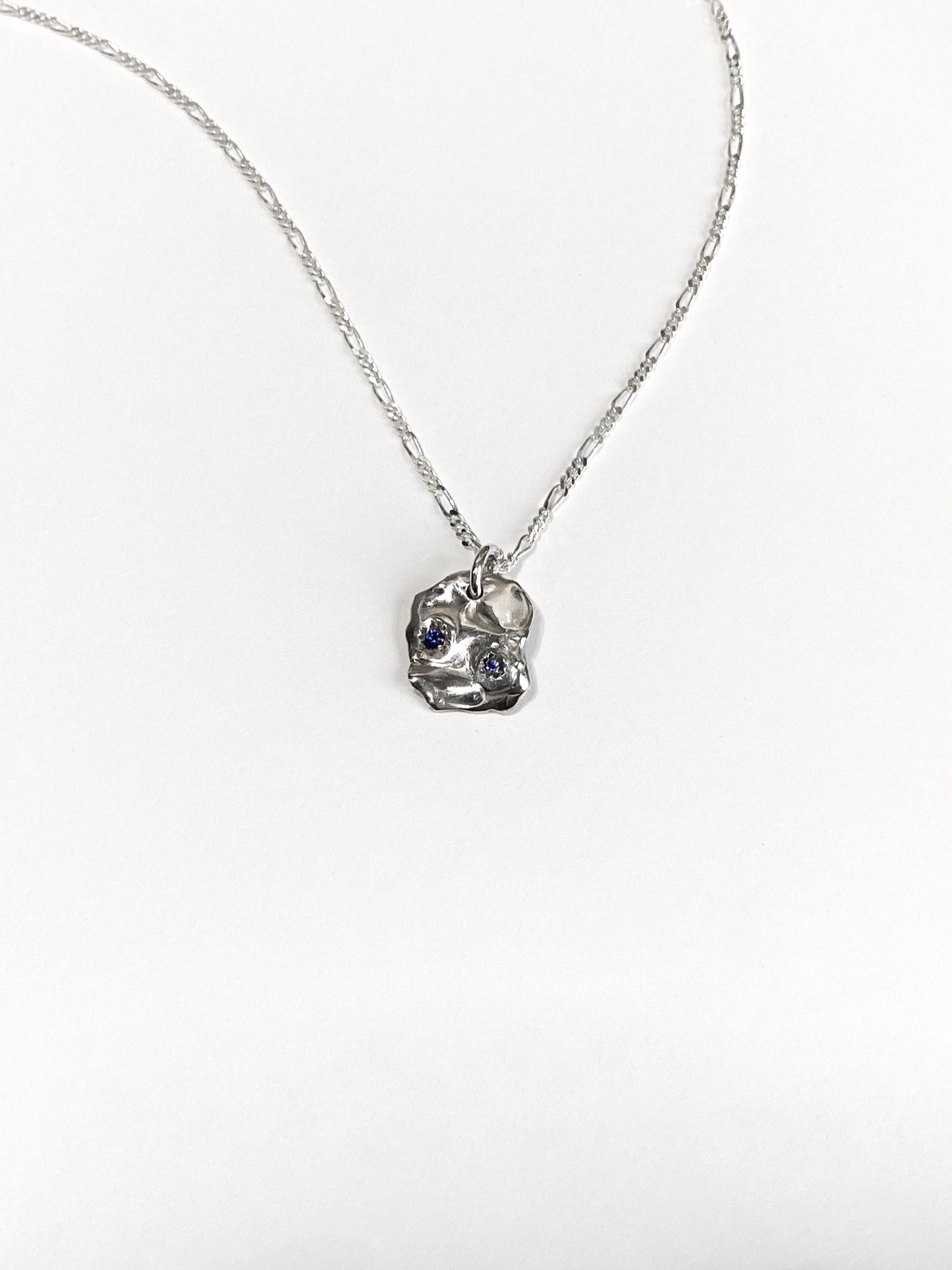 Silver molten pendant with 2 blue sapphires on chain on white background
