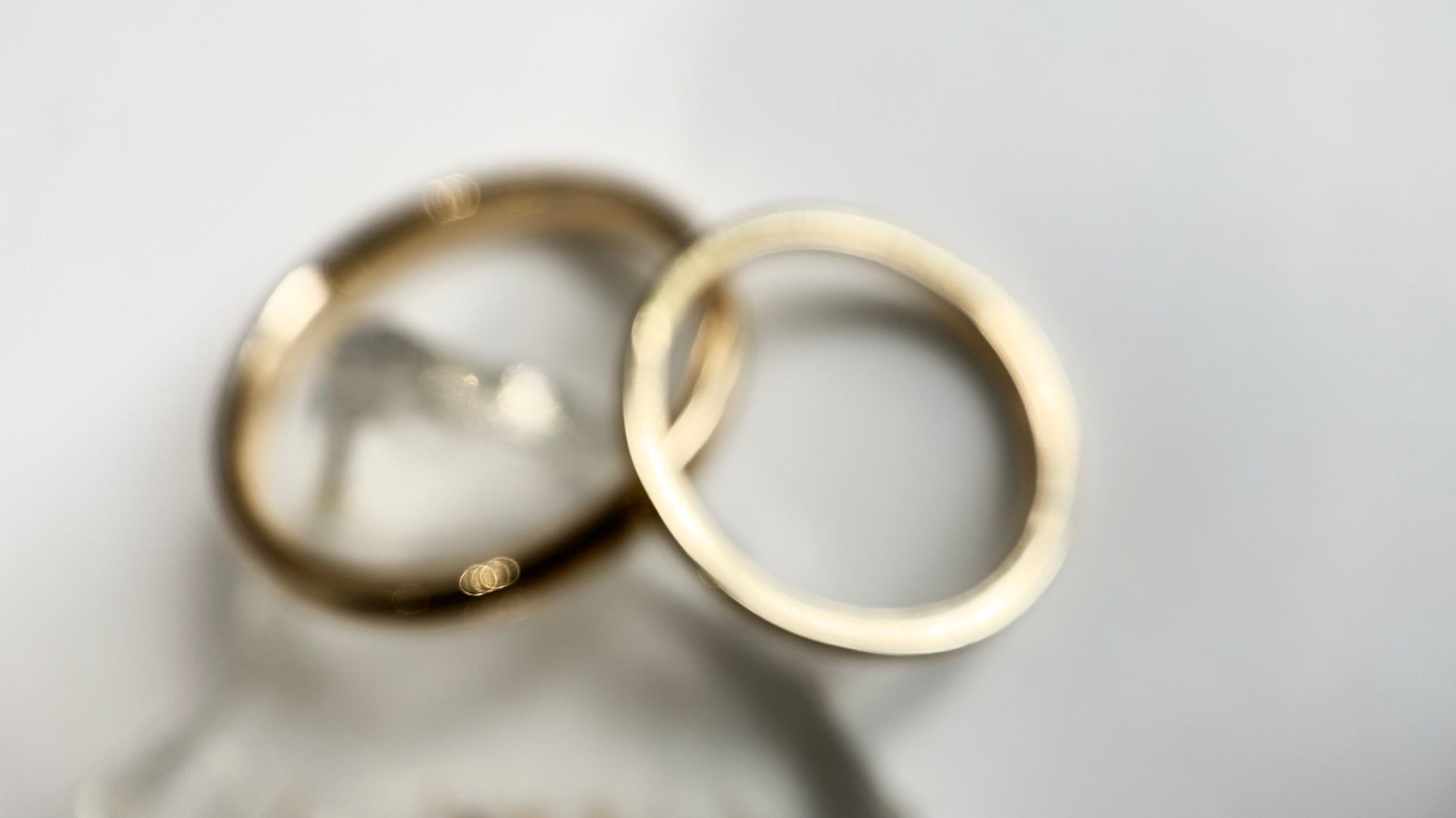 2 yellow gold wedding rings out of focus on white background