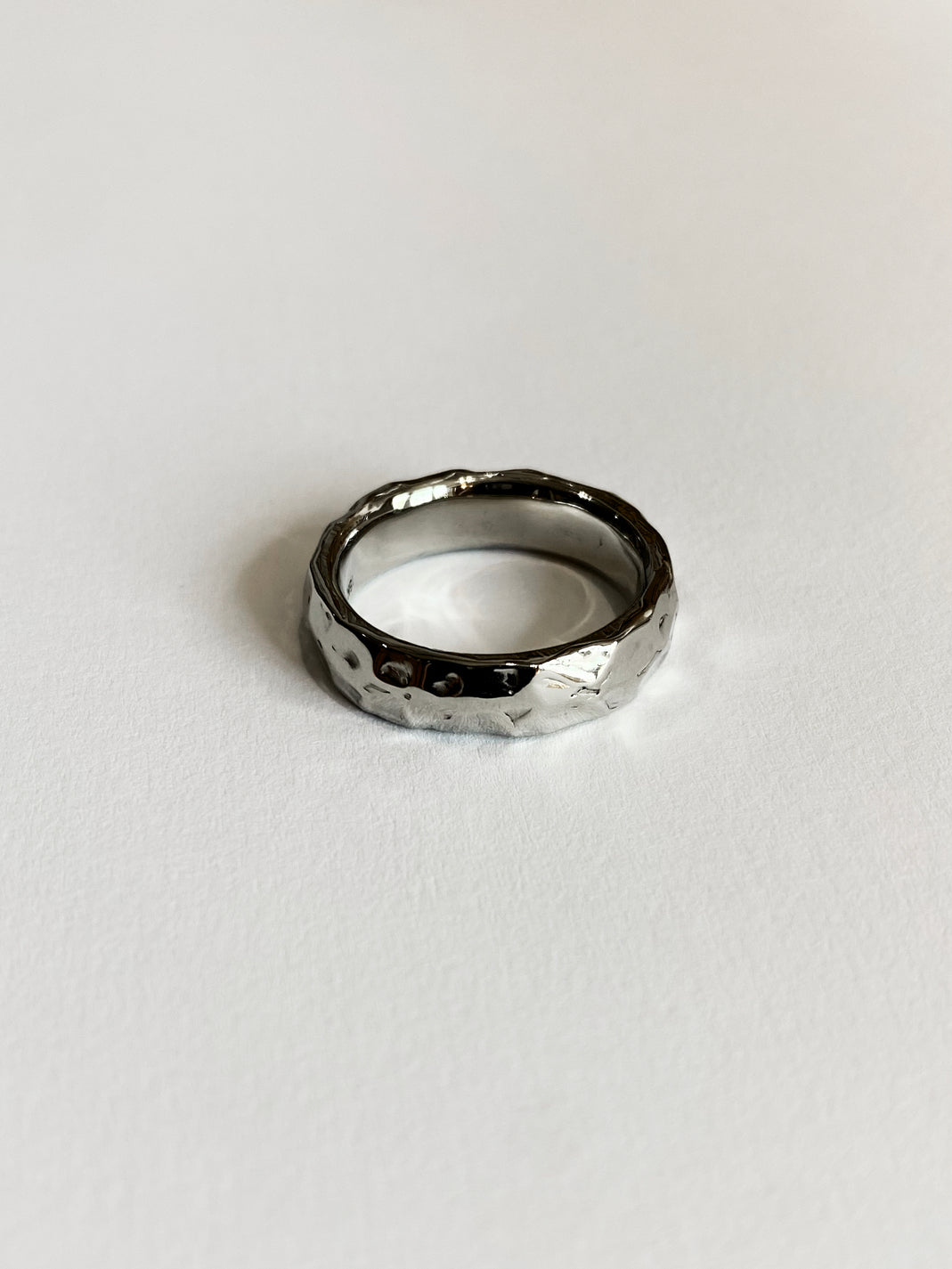 textured white gold ring on white background