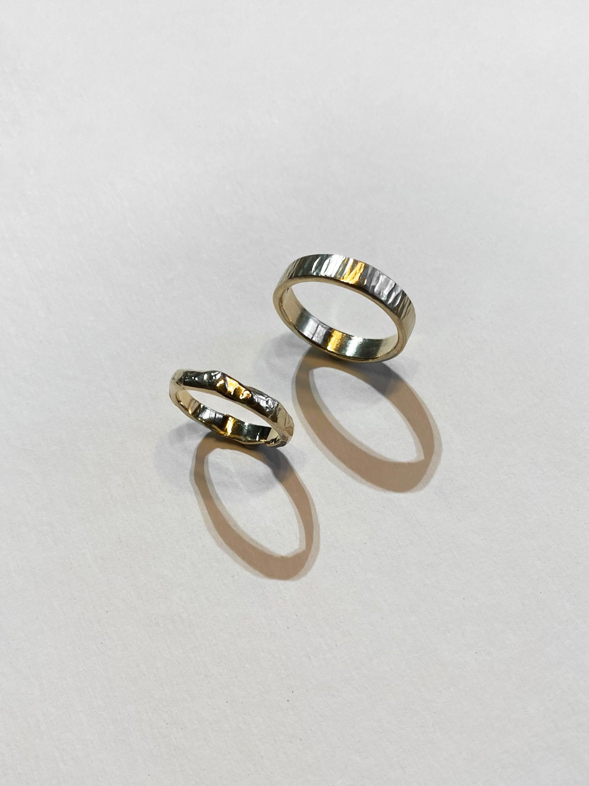 Two textured and molten wedding rings on white background