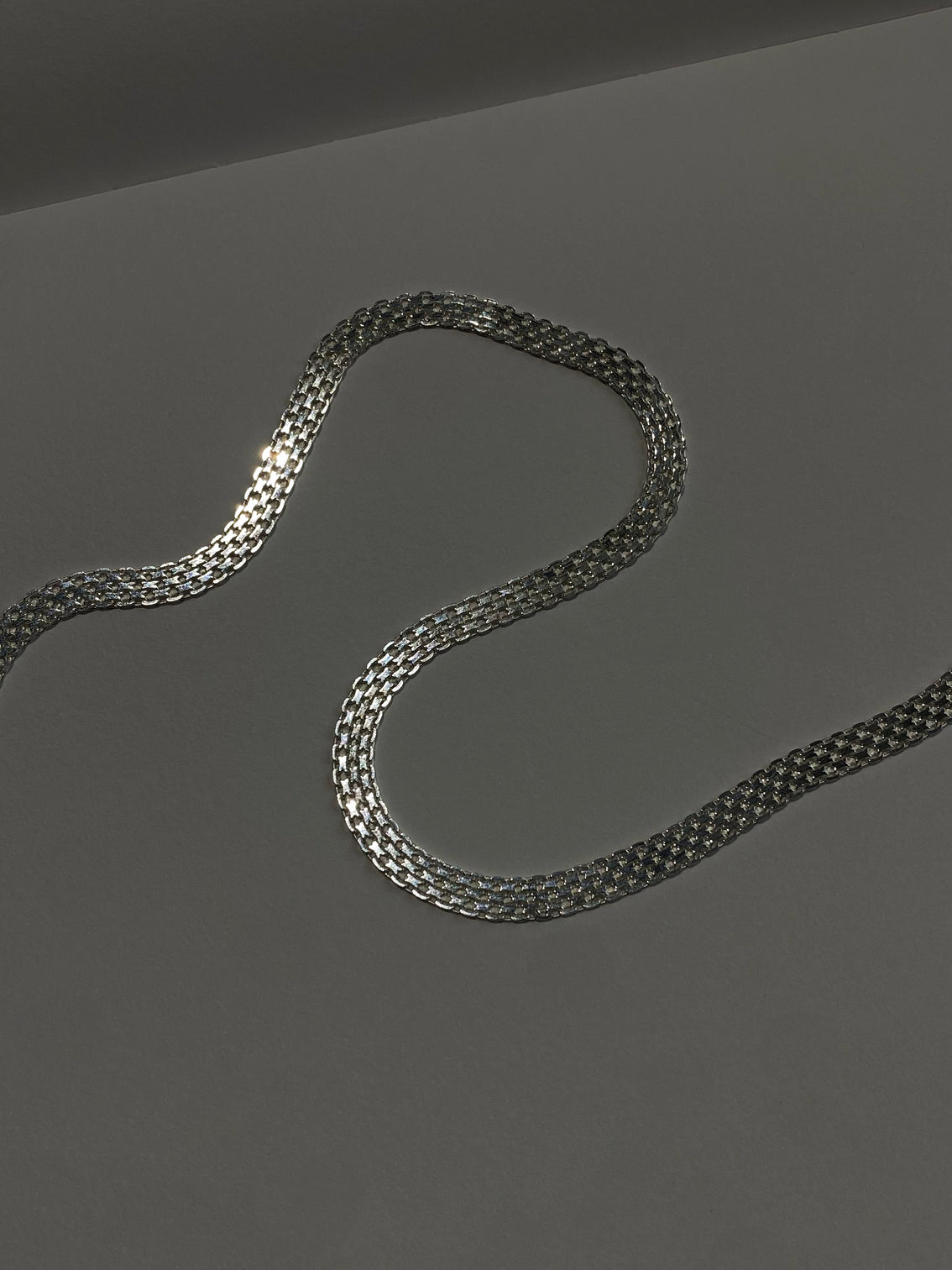 Silver checkered link wide chain on dark background