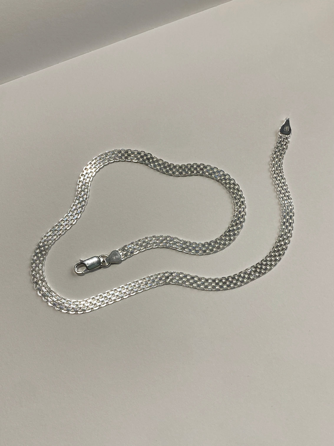 Silver checkered link wide chain on white background