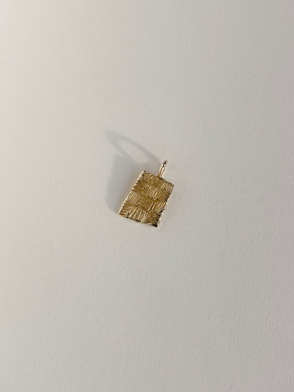 Gold rectangular pendant with checker lines on white background