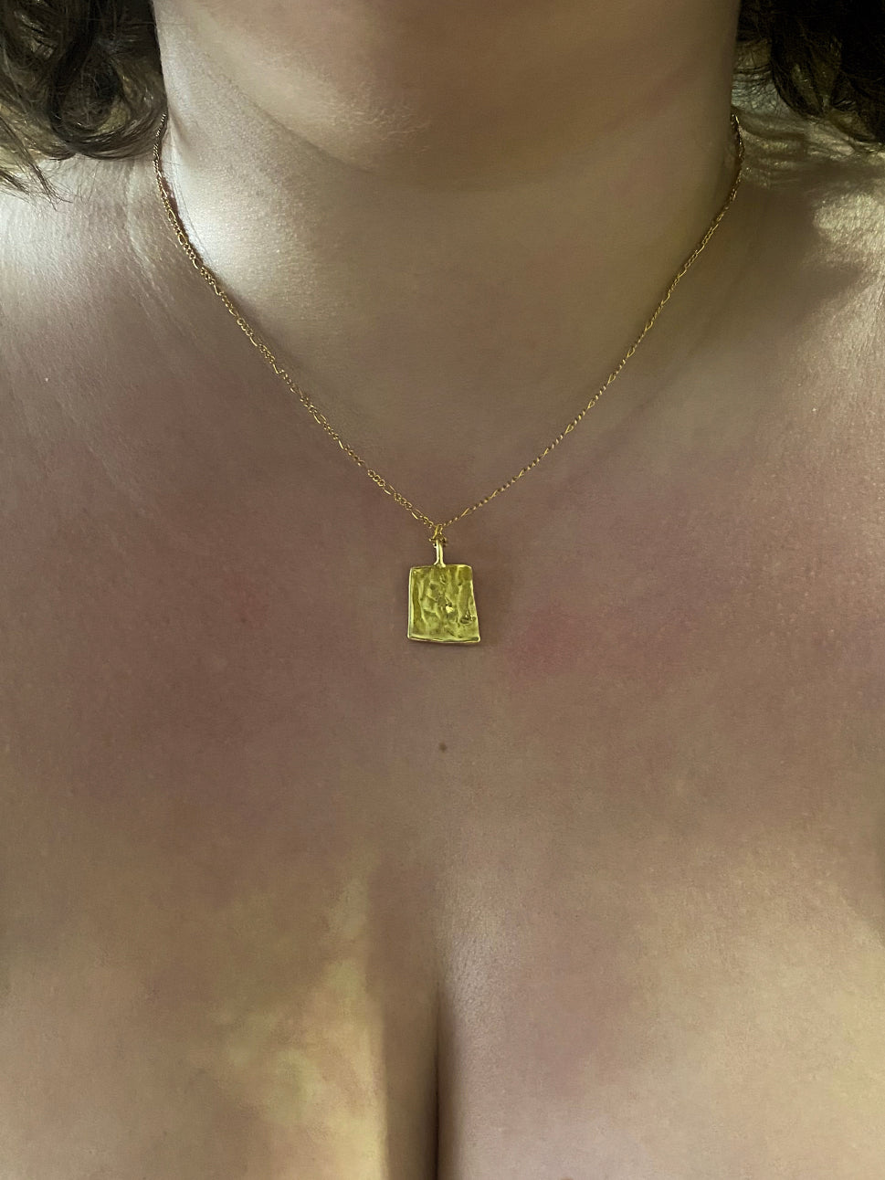 Back of gold rectangular pendant with checker lines on chain