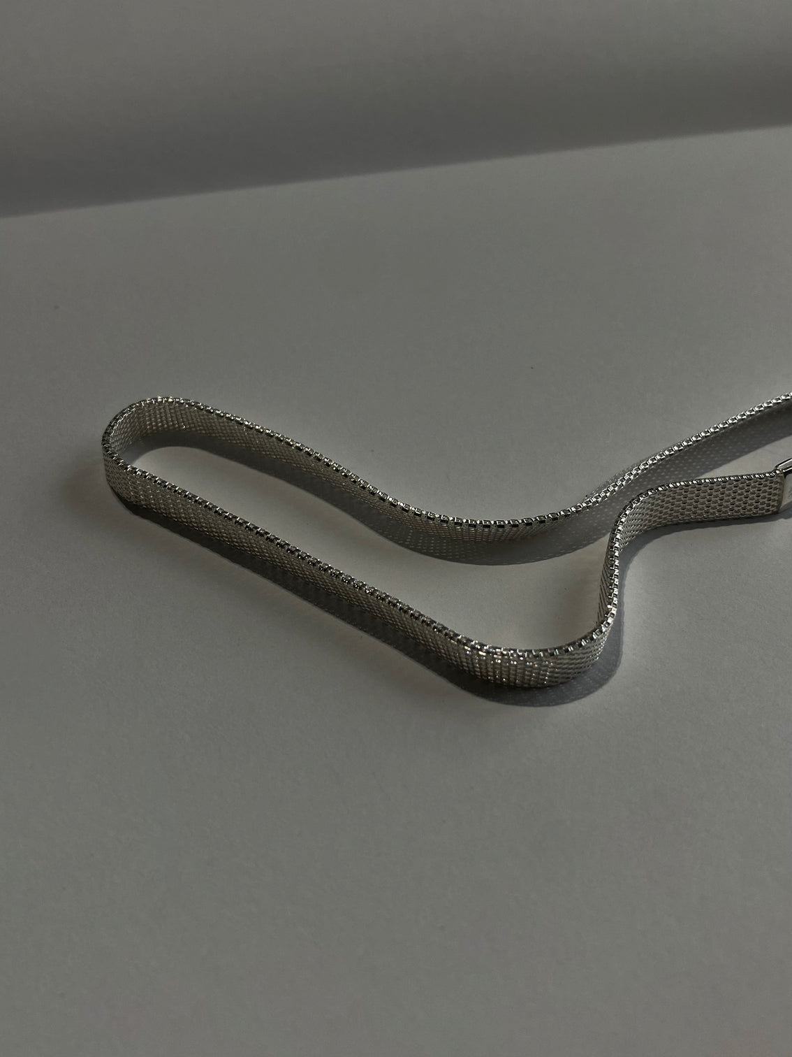 Wide silver chain laying on grey sheet