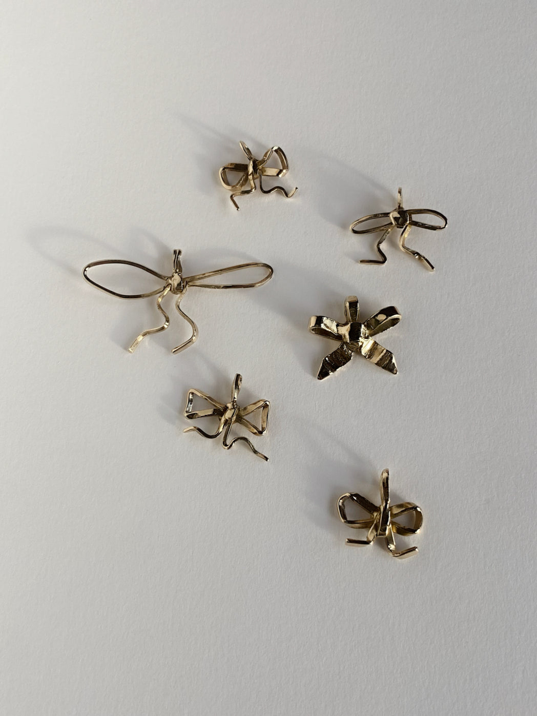 6 gold bow pendants on white background