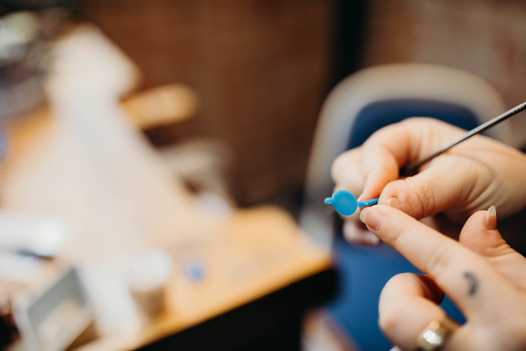 Blurry background of work bench with hands up front pointing at a wax pendant