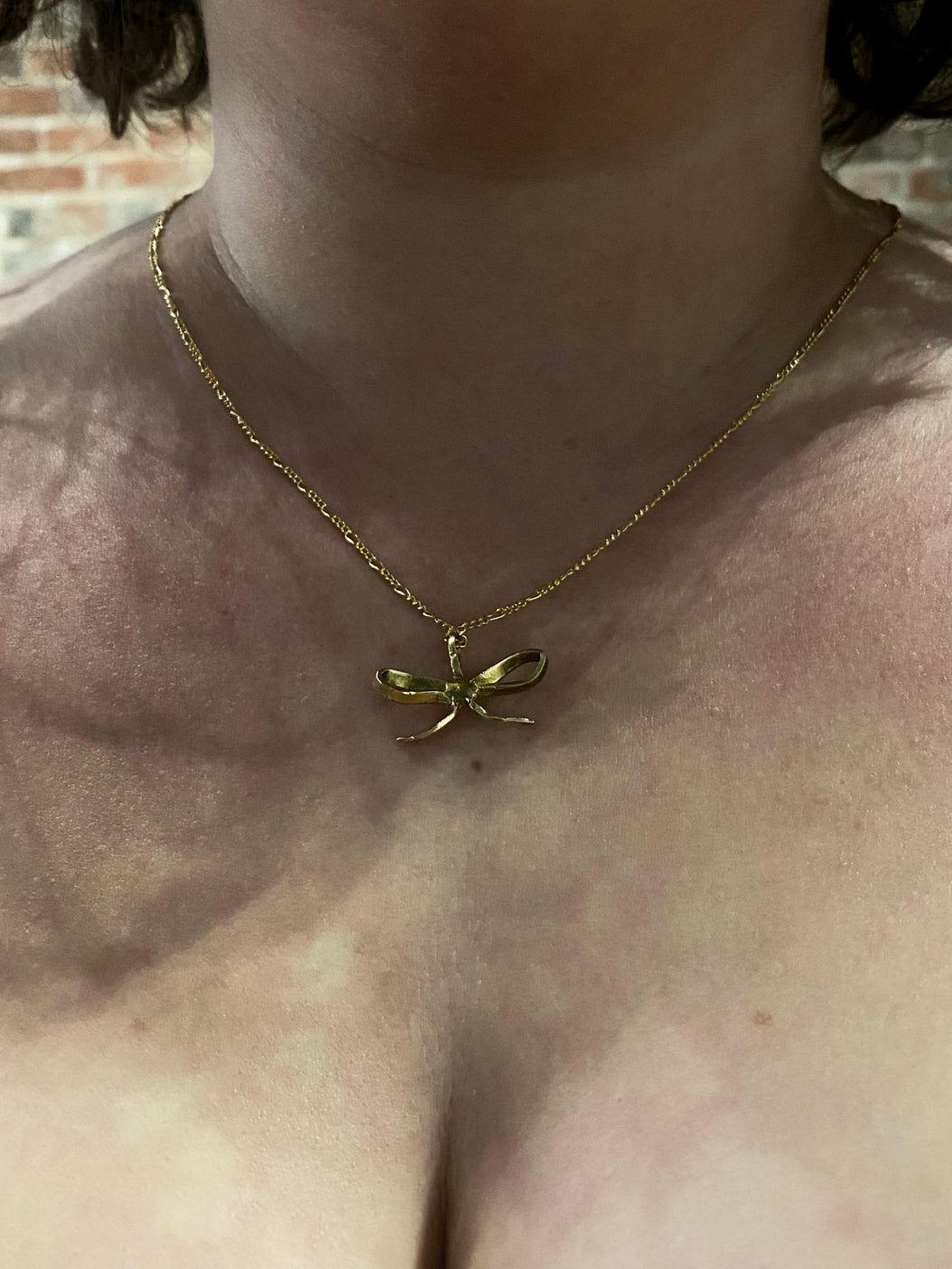 Gold bow pendant on model with short hair