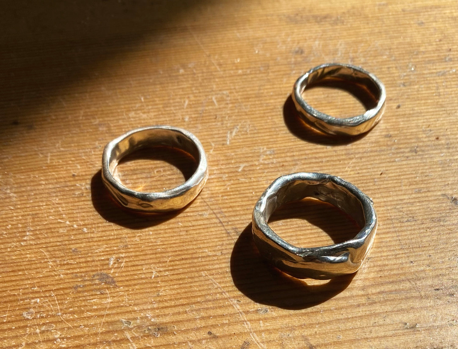 3 molten silver rings on wood 