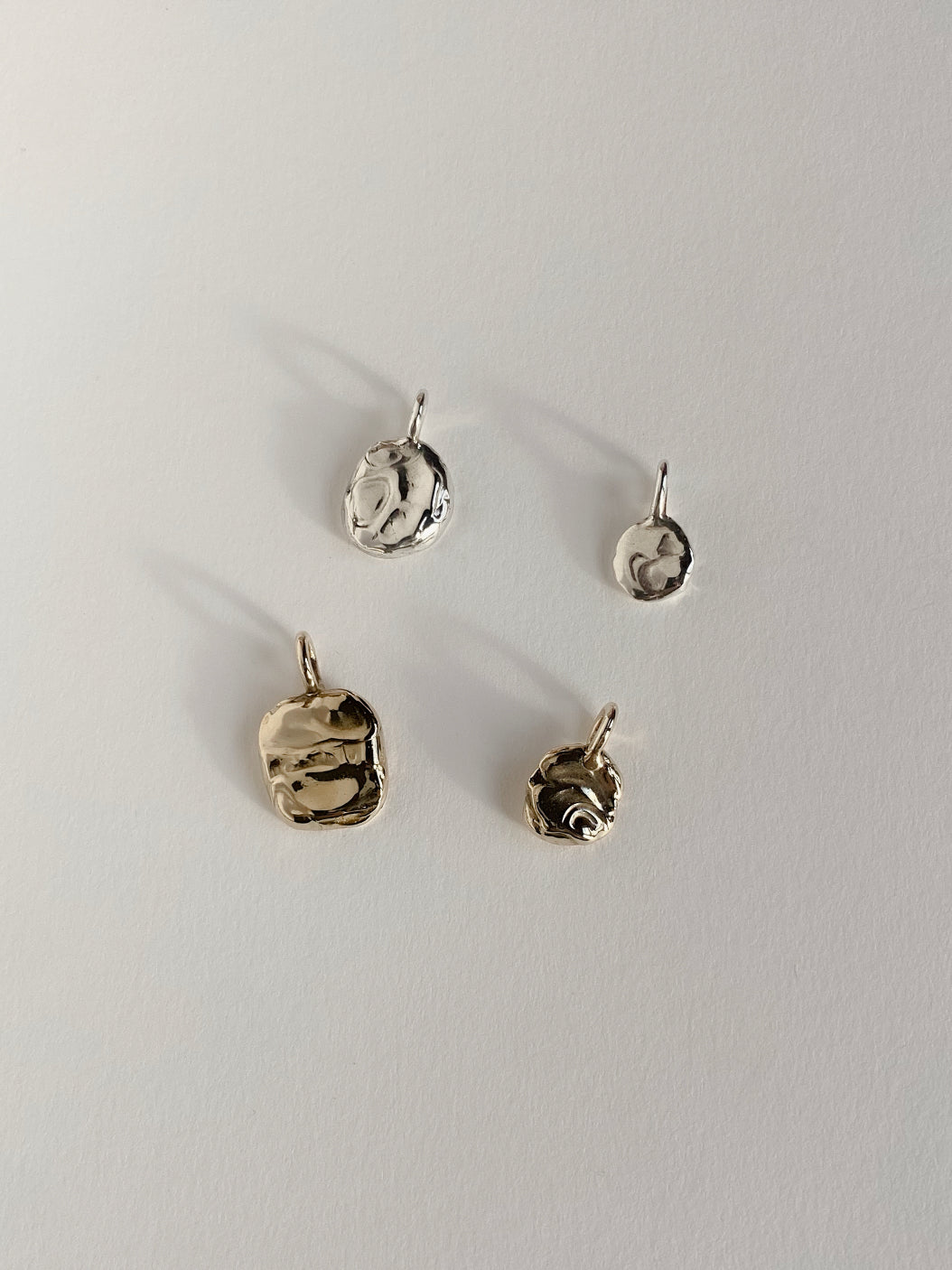2 silver and 2 gold textured molten pendants on white background