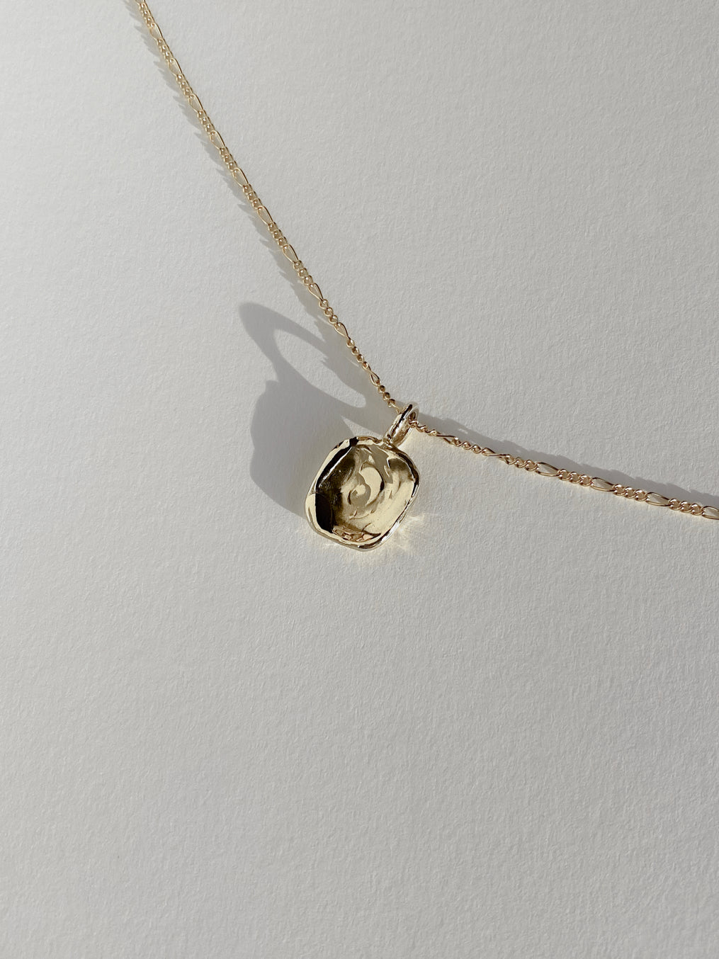 Textured gold molten pendant necklace on white background