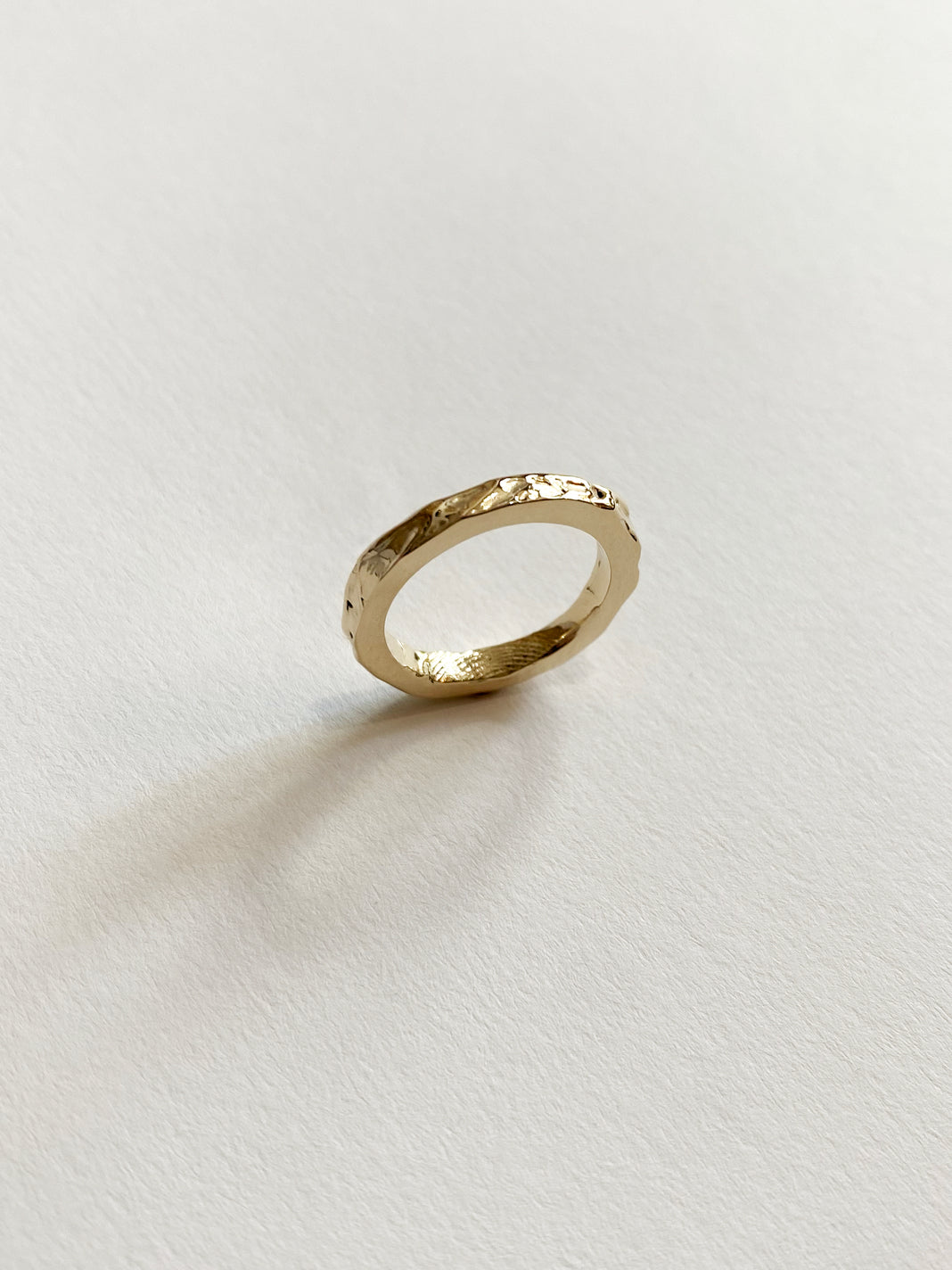 a shiny yellow gold band ring with a crinkled molten texture on the outside and a fingerprint on the inside