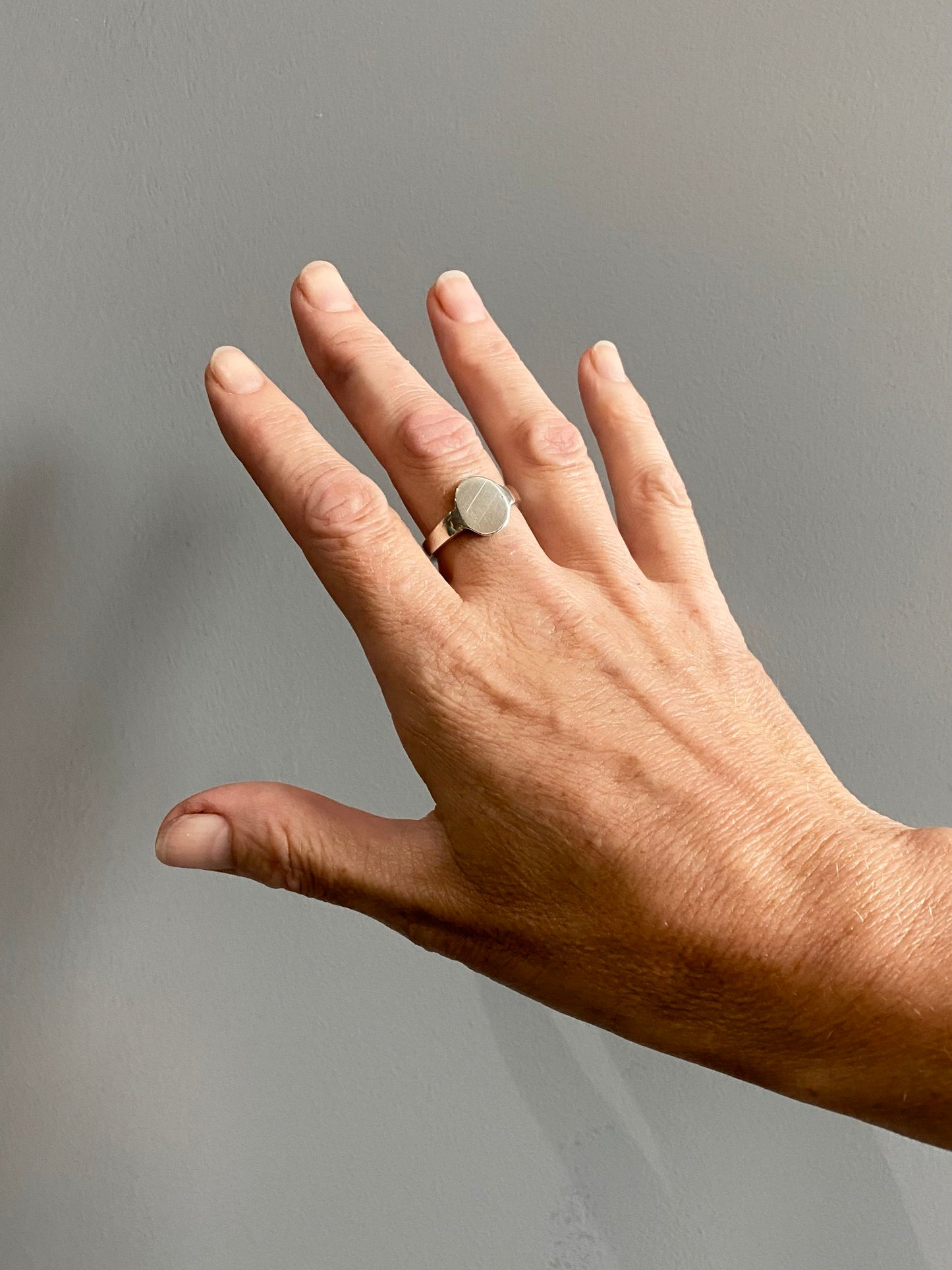 Silver oval signet ring on hand