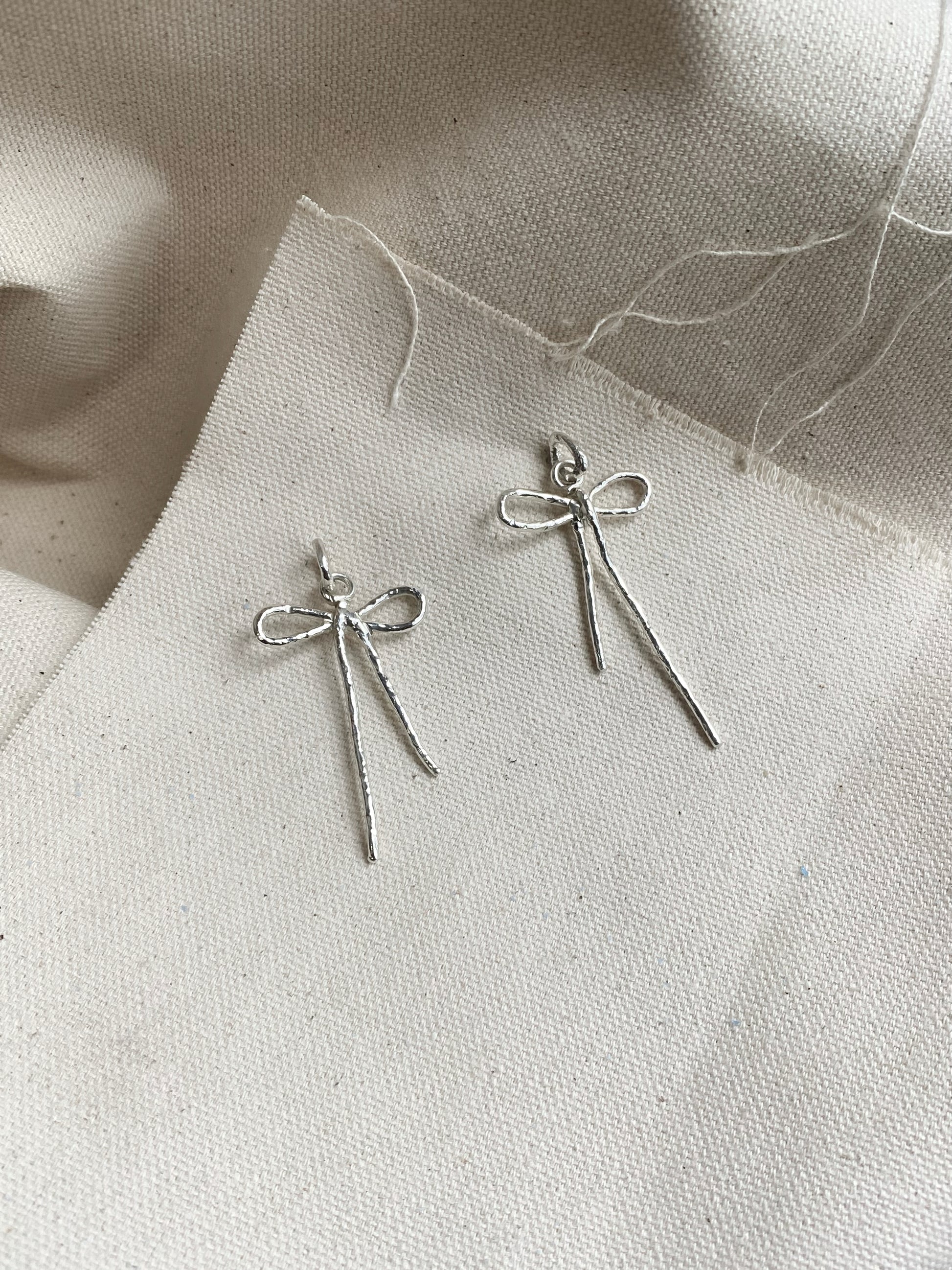 Sterling silver bow earrings laying on canvas