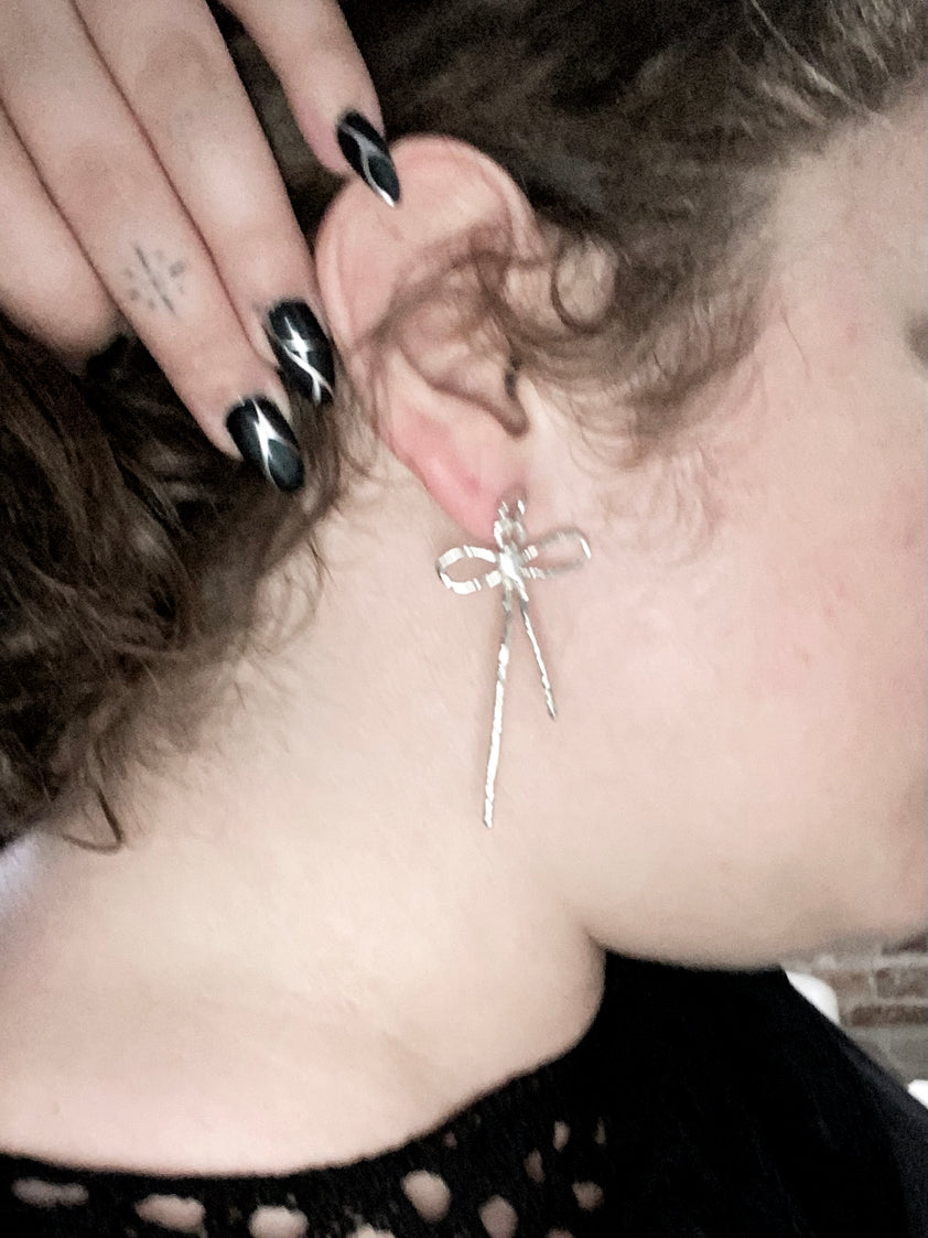 Sterling silver bow earrings on model with curly hair