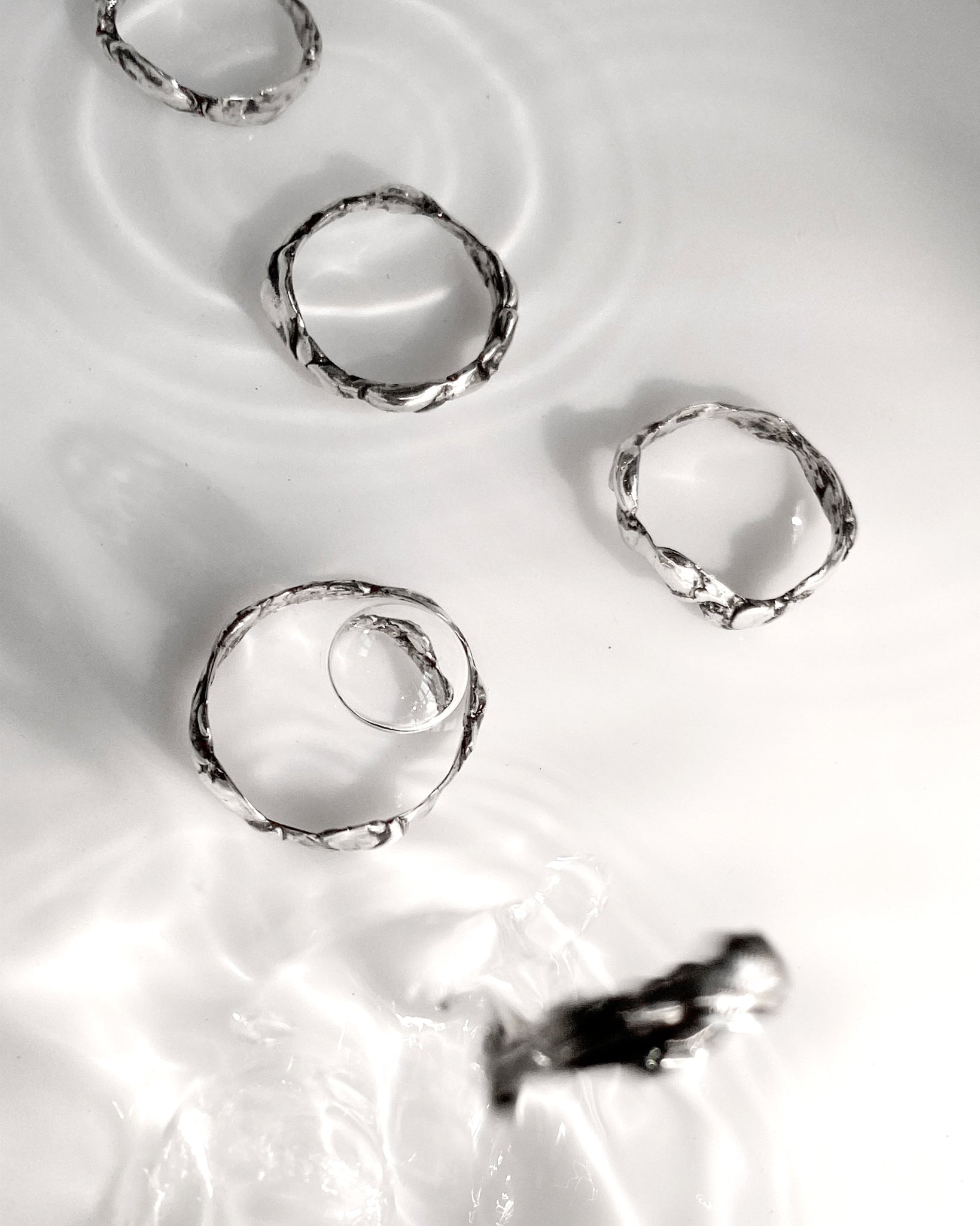 5 silver molten rings dropped in water