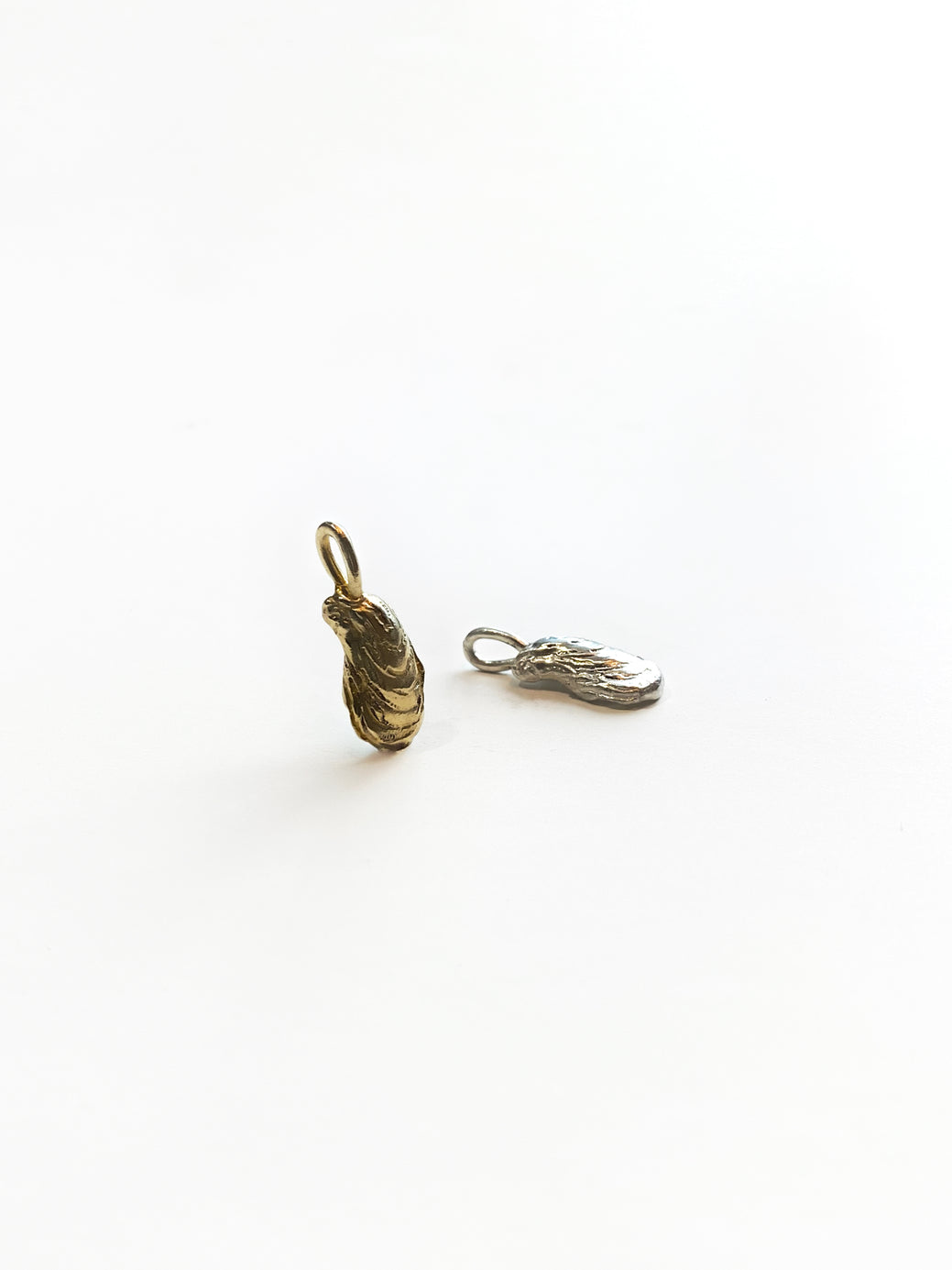 Gold and silver oyster charms on white background