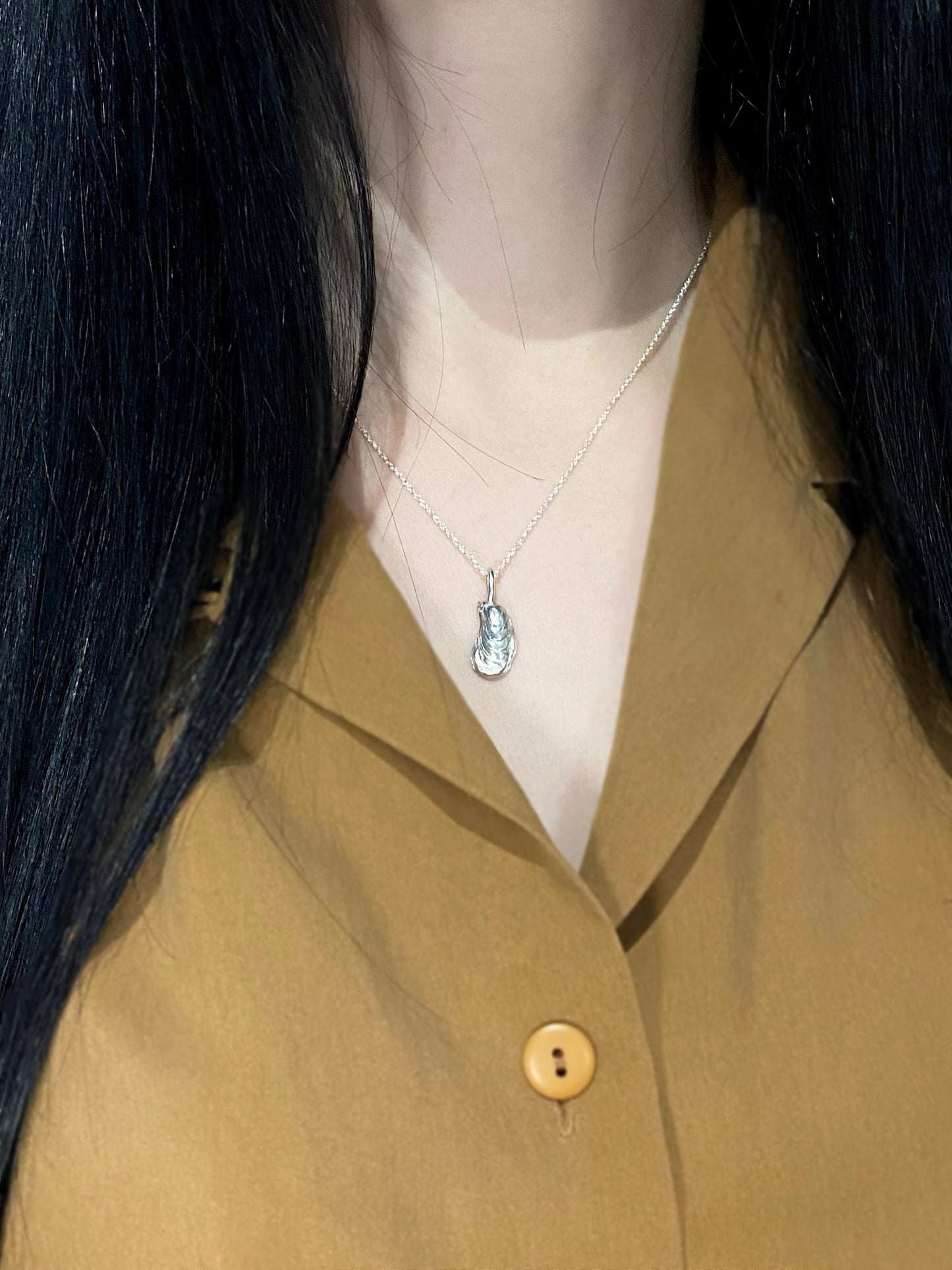 Silver oyster necklace on model with brown shirt