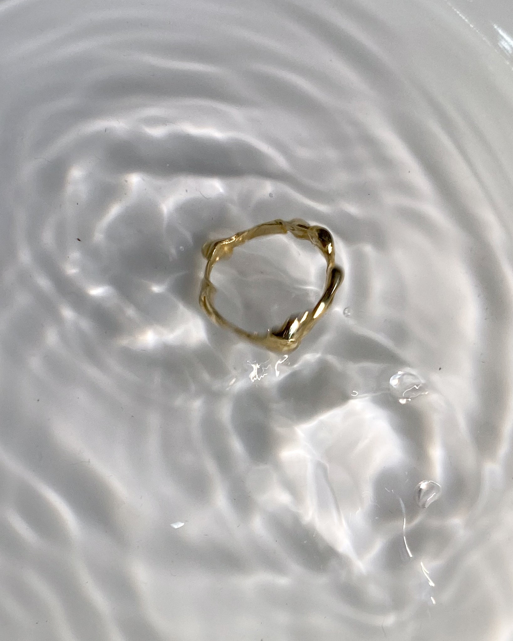 Gold molten ring falling into water
