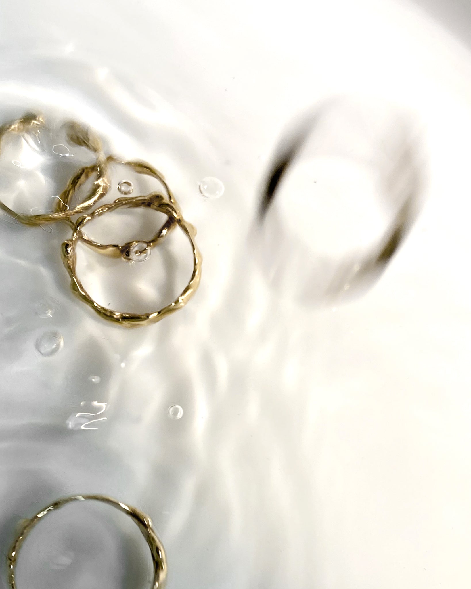 5 gold molten rings falling into water