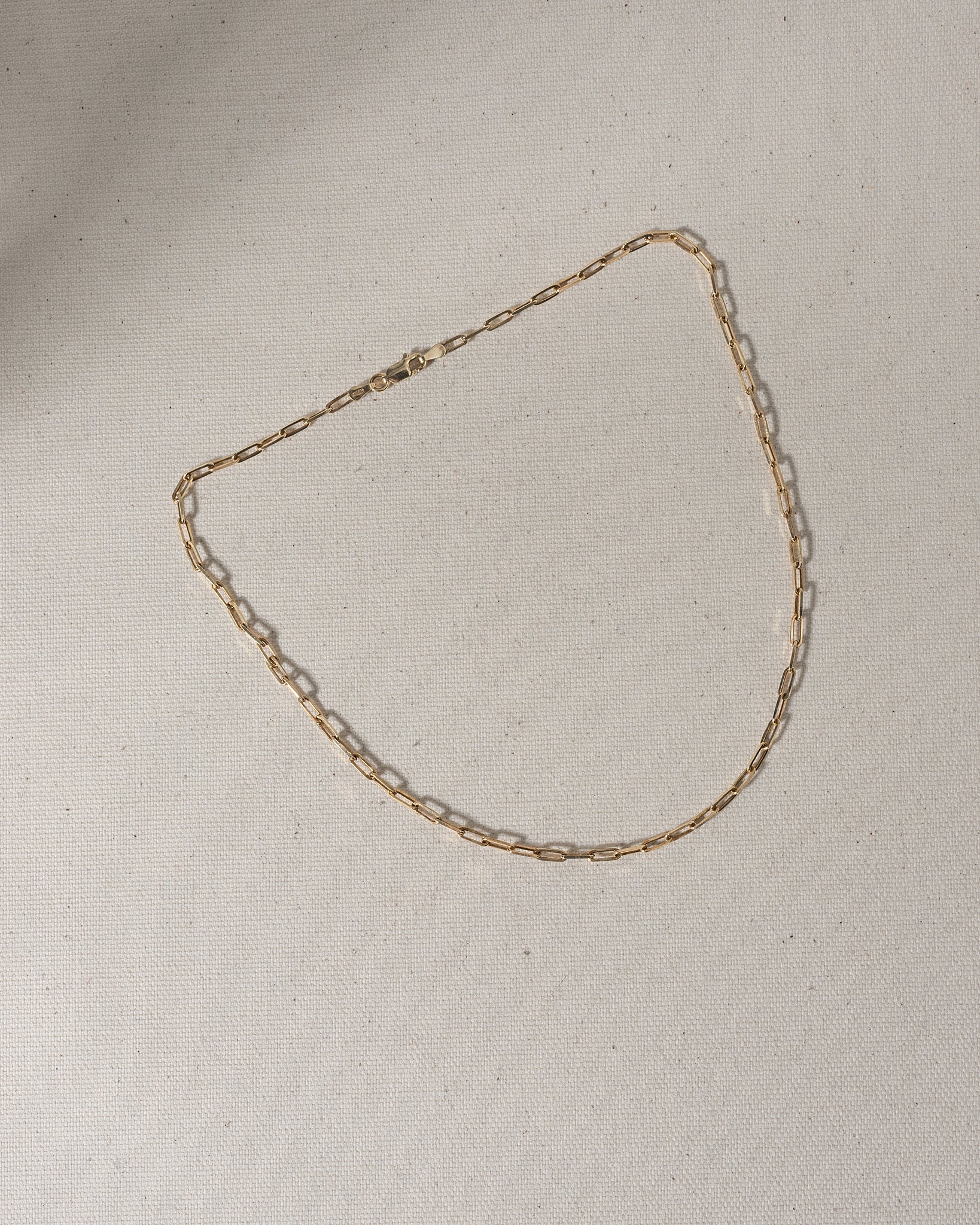 Gold chain with large oval links laying on canvas