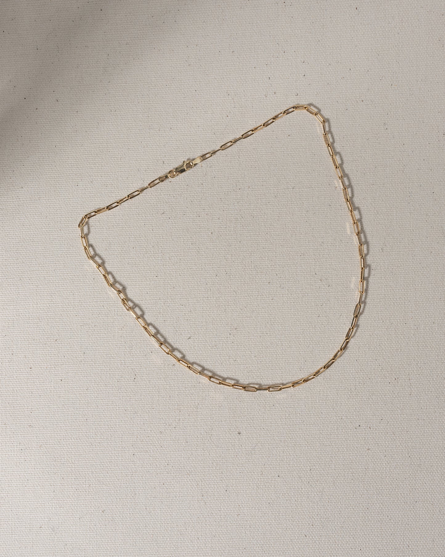 Gold chain with large oval links laying on canvas