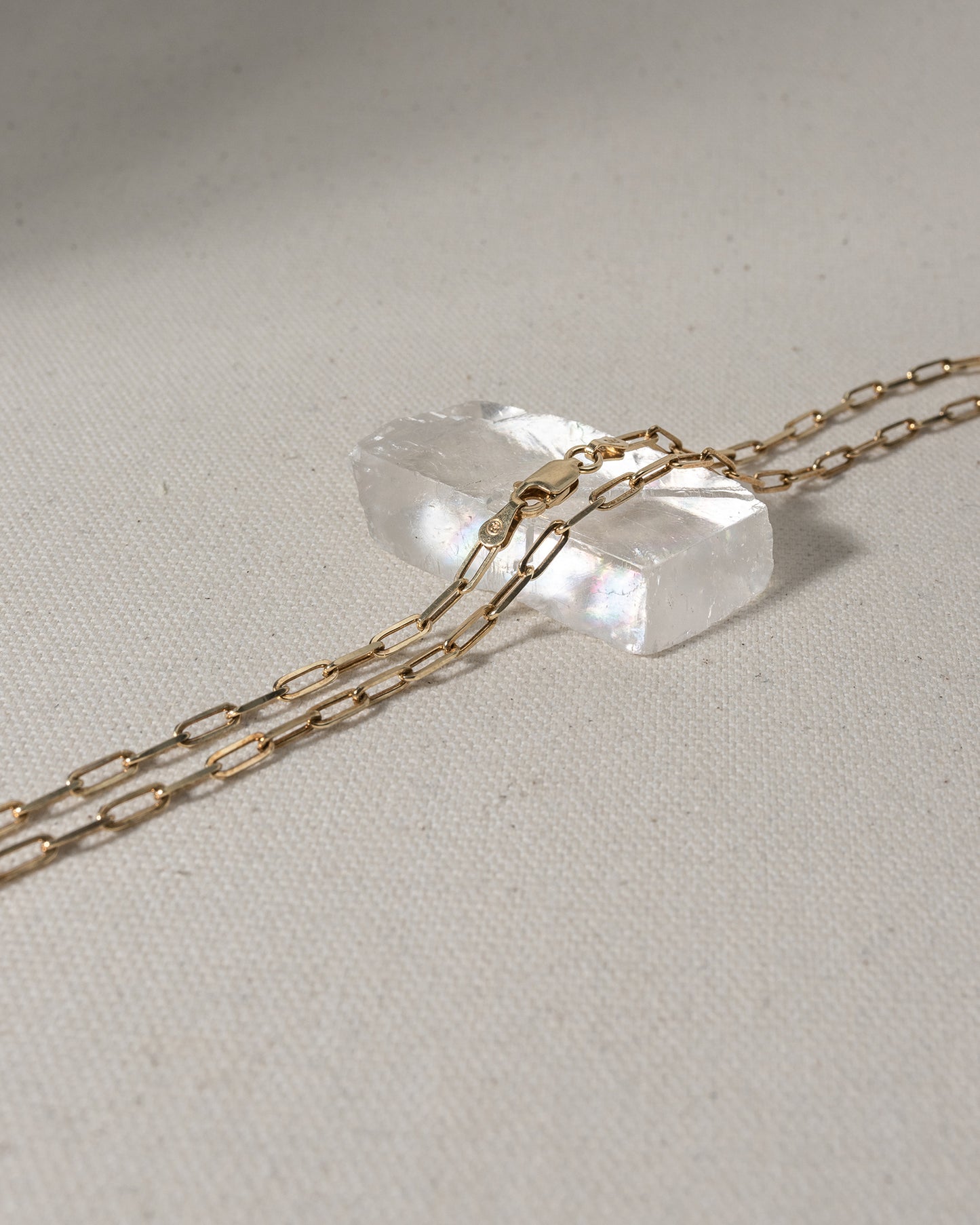 Gold chain with large oval links laying on glass piece