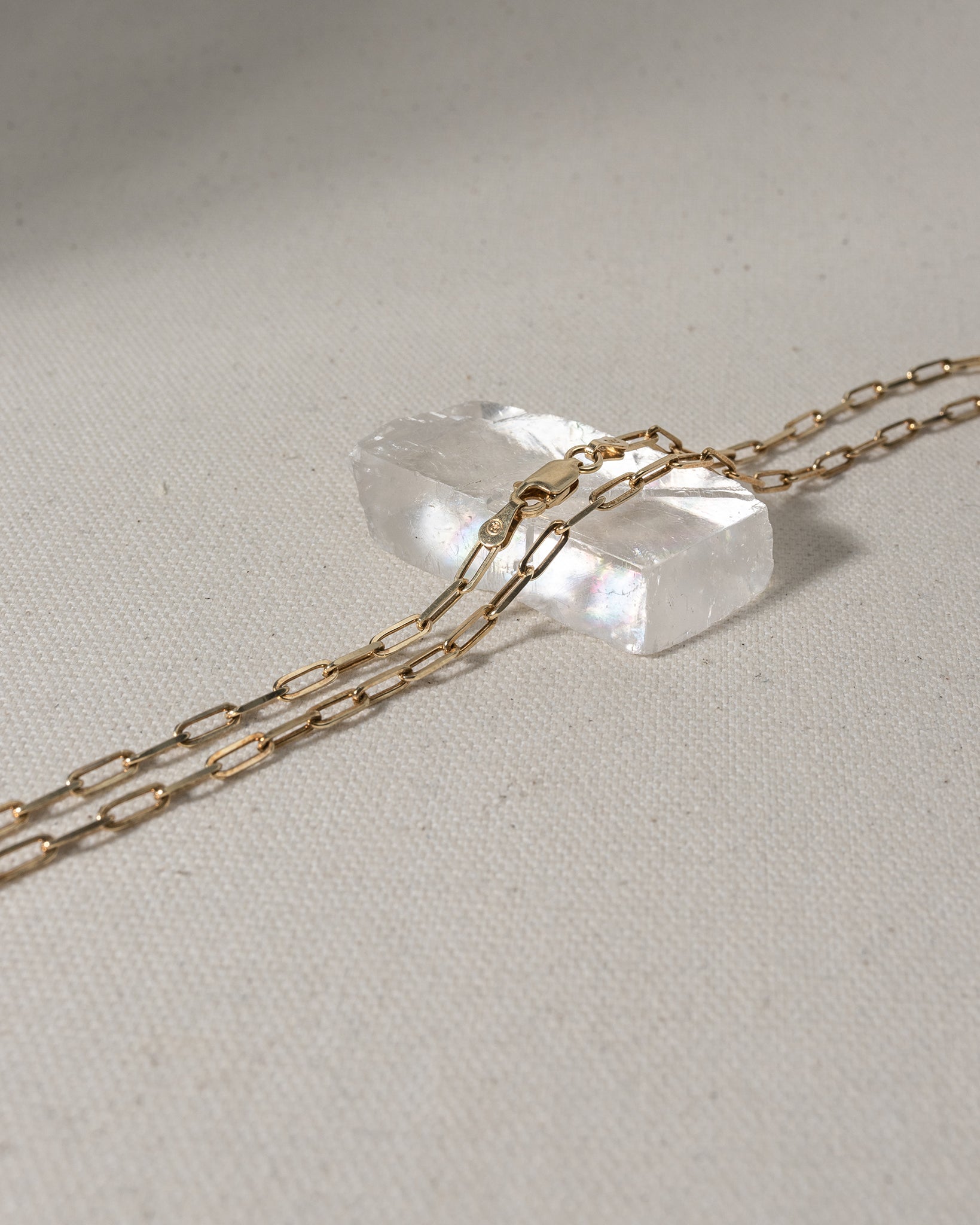 Gold chain with large oval links laying on glass piece