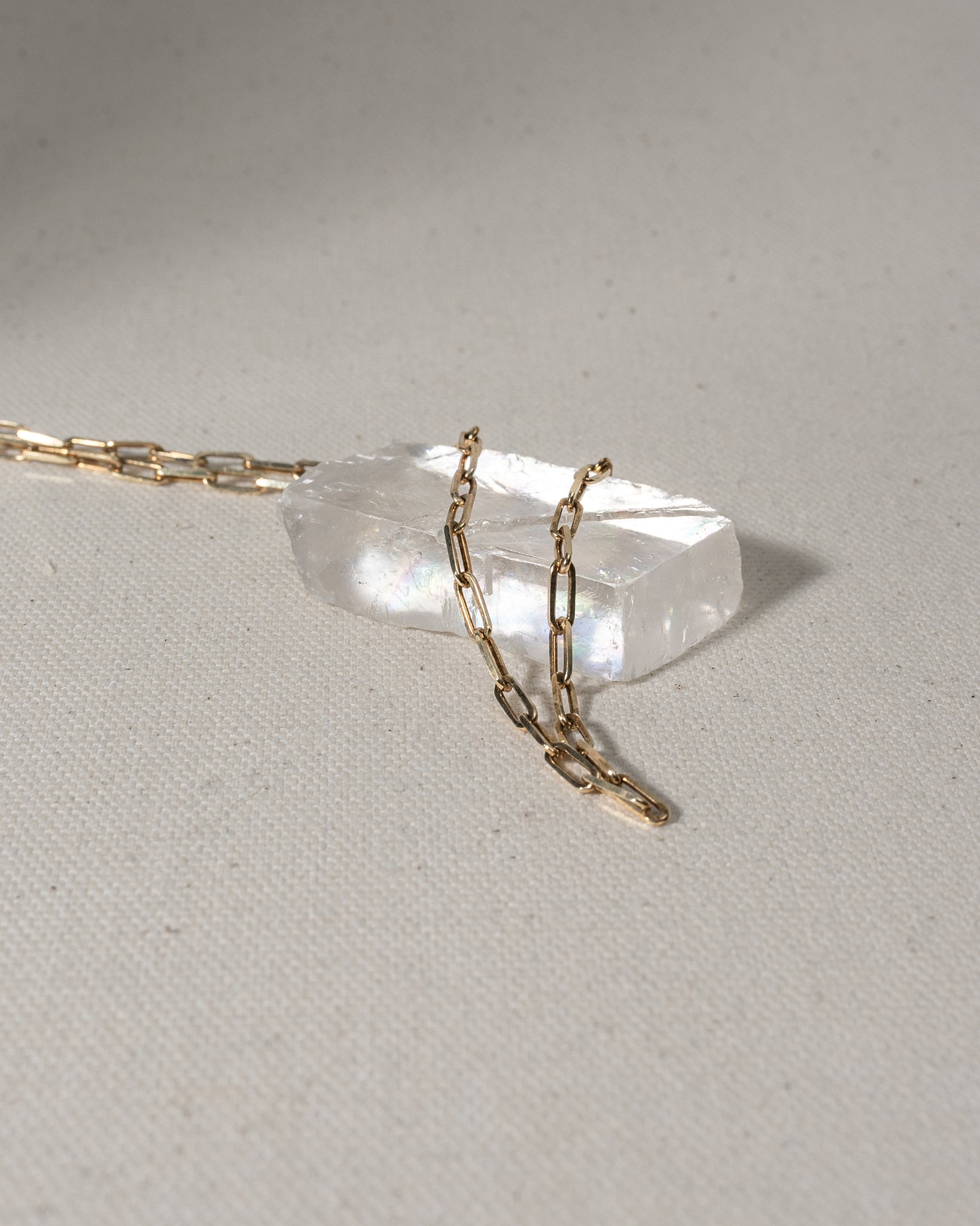 Gold chain with large oval links laying on glass piece