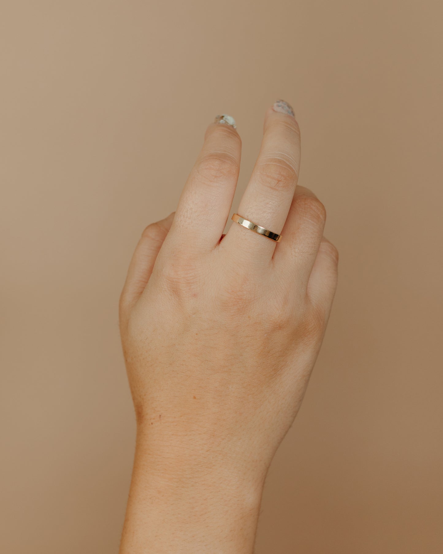 Simple flat gold ring on hand