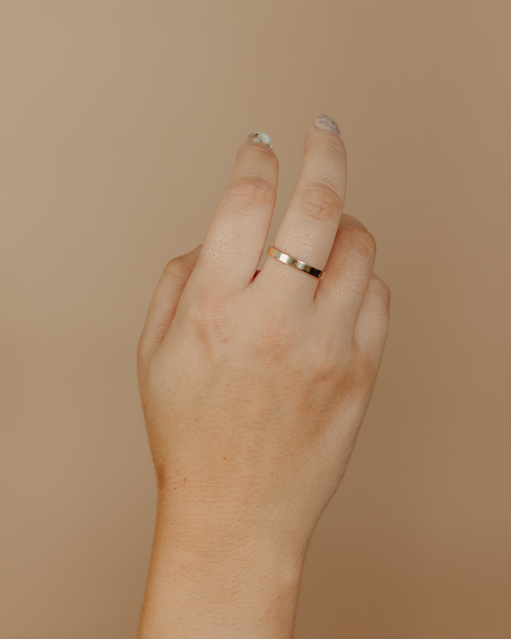 Simple flat gold ring on hand