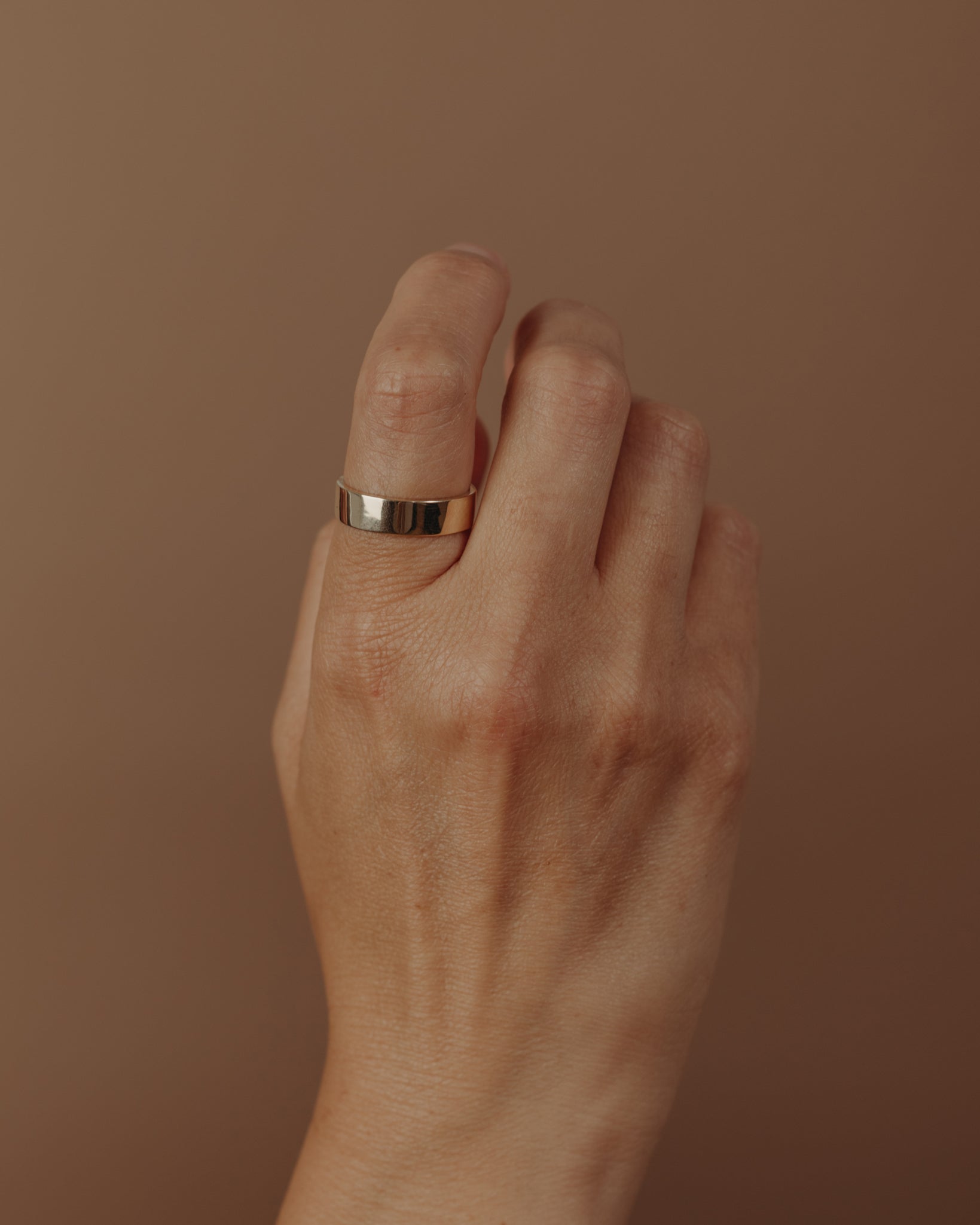 Simple flat gold ring on hand